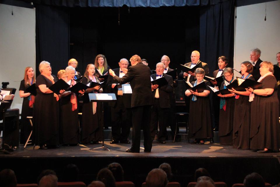 A choir is performing on stage with conductor.